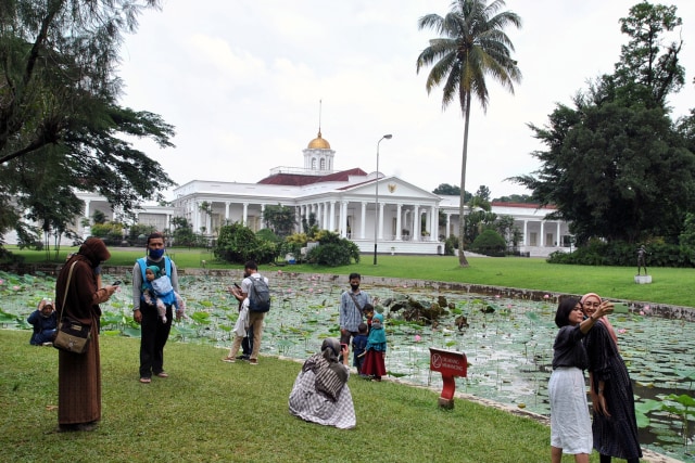 Sejumlah pengunjung berfoto dengan latar belakang Istana Kepresidenan di kawasan Kebun Raya Bogor, Jawa Barat, Minggu (1/11).  Foto: Arif Firmansyah/ANTARA FOTO