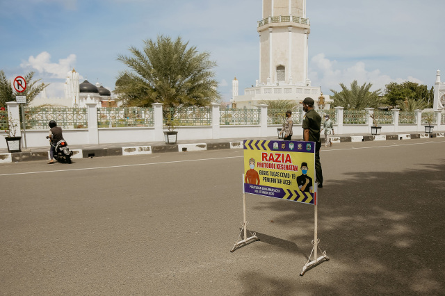 Seorang pemotor terlihat berbalik arah kendaraan saat razia protokol kesehatan di depan Masjid Raya Baiturrahman, Aceh, Senin (2/11). Foto: Abdul Hadi/acehkini