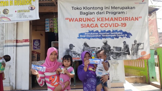 Salah satu warga Desa Suling Bagon, Jember, sedang memegang voucher program Warung Kemandirian yang bisa ditukarkan dengan bahan pokok. 