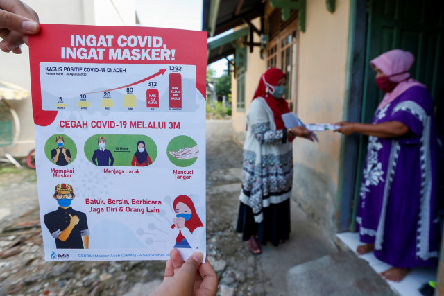 Petugas kesehatan dari Puskesmas Ulee Kareng (kiri) mensosialisasikan protokol kesehatan yang dianjurkan pemerintah guna mencegah penyebaran dan penularan COVID-19 di sela pelaksanaan imunisasi balita di Desa Ilie, Banda Aceh, Aceh. Foto: Irwansyah Putra/ANTARA FOTO