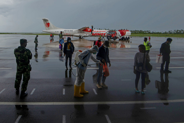 Petugas menyemprotkan cairan disinfektan pada penumpang pesawat komersial Wings Air asal Batam usai mendarat di Bandara Raden Sadjad, Ranai, Kabupaten Natuna, Kepulauan Riau, Selasa (17/11). Foto: Aditya Pradana Putra/Antara Foto