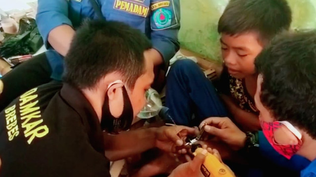 Dengan alat gerinda, petugas Damkar Brebes berusaha mencopot cincin dari jari anak remaja asal Banjaratma.