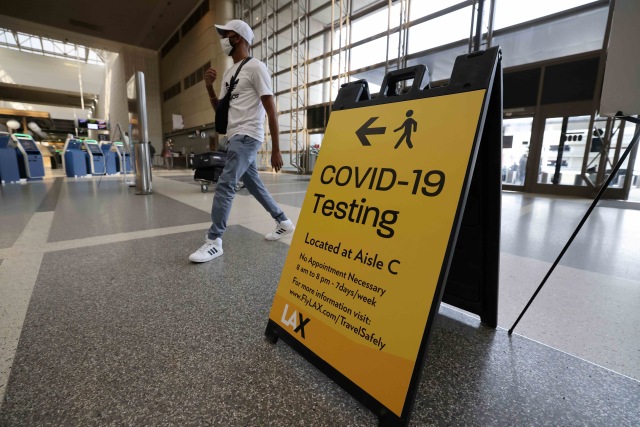 Seseorang melewati papan informasi di terminal internasional Tom Bradley di bandara LAX, di Los Angeles, California, Amerika Serikat. Foto: Lucy Nicholson/Reuters