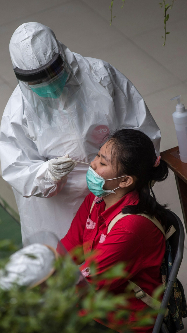Seorang petugas medis mengambil sampel dari seorang siswa sekolah menengah untuk menguji virus Corona, di Surabaya. Foto: AFP/JUNI KRISWANTO
