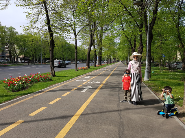 Trotoar yang lebar dengan udara yang segar, dedaunan yang hijau, serta bunga yang berwarna-warni membuat anak-anak senang bermain skuter di jalan (foto: dokumentasi pribadi) 