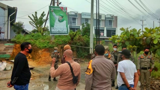 ANGGOTA Satuan Polisi Pamong Praja (Satpol PP) Pekanbaru didukung oleh anggota Polisi bersiap-siap menurunkan baliho Habib Rizieq di Jalan Air Hitam. 