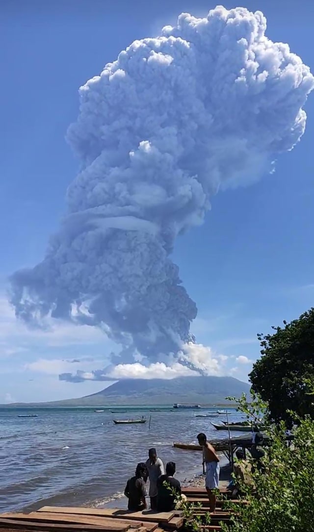 Warga berkumpul untuk menyaksikan Gunung Ili Lewotolok menyemburkan abu saat erupsi gunung berapi di Lembata, Nusa Tenggara Timur, Minggu (29/11). Foto: Joy Christian/AFP
