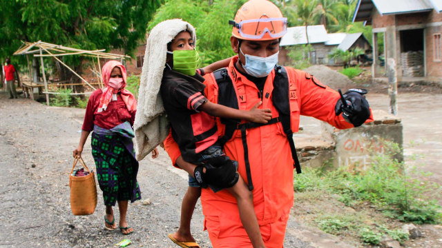 Seorang anggota Basarnas menggendong bocah ketika tim gabungan mengevakuasi warga yang masih bertahan dalam Kawasan Rawan Bencana (KRB) III erupsi Gunung Ili Lewotolok di Kecamatan Ile Ape Timur, NTT Kamis (3/12/2020). Foto: Kornelis Kaha/ANTARA FOTO