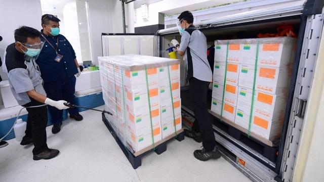 Petugas menyemprotkan disinfektan ke kontainer berisi vaksin COVID-19 Sinovac saat tiba di Bio Farma, Bandung, Jawa Barat. Foto: Muchlis Jr/Biro Pers Sekretariat Presiden