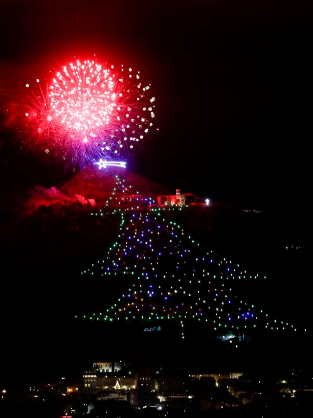 Kembang api meledak saat pohon Natal terbesar di dunia menyala di lereng Gunung Ingino di kota abad pertengahan Gubbio, Italia, Senin (7/12). Foto: Yara Nardi/REUTERS