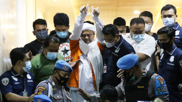 Imam Besar Front Pembela Islam (FPI) Habib Rizieq Shihab (tengah) berjalan menuju mobil tahanan usai diperiksa di Mapolda Metro Jaya, Jakarta, Minggu (13/12/2020) dini hari. Foto: Antara/Hafiz Mubarak