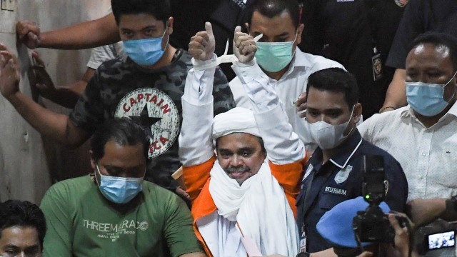 Imam Besar Front Pembela Islam (FPI) Habib Rizieq Shihab (tengah) berjalan menuju mobil tahanan usai diperiksa di Mapolda Metro Jaya, Jakarta, Minggu (13/12/2020) dini hari. Foto: Antara/Hafiz Mubarak