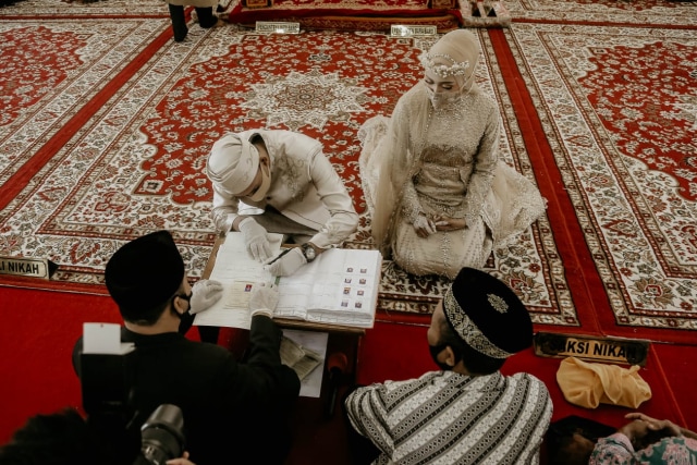 Pasangan pengantin terlihat mengenakan masker saat prosesi pernikahan di Masjid Haji Keuchik Leumiek, Banda Aceh. Foto: Abdul Hadi/acehkini