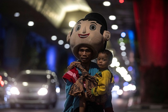 Wahyu bersama anaknya saat mengamen sebagai badut di Jalan Pangeran Antasari, Jakarta Selatan. Foto: Sigid Kurniawan/Antara Foto