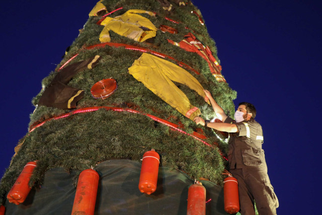 Sebuah pohon Natal dihiasi dengan seragam petugas pemadam kebakaran dan penyelamat di Beirut, Lebanon, Minggu (20/12/2020). Foto: Mohamed Azakir/REUTERS