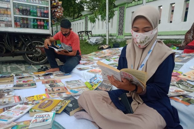 Warga di Aceh Barat membaca buku di Lapak Baca, program membaca buku gratis di ruang publik. Foto: Siti Aisyah/acehkini
