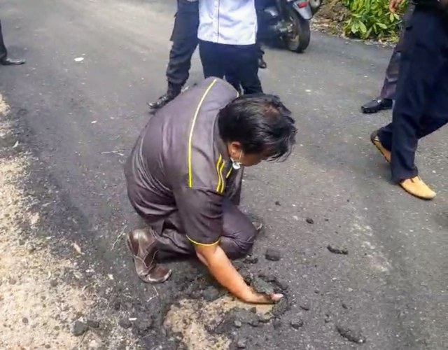 Anggota DPRD Muara Enim, Sumsel, saat mengeruk permukaan aspal menggunakan tangannya. (foto: istimewa)