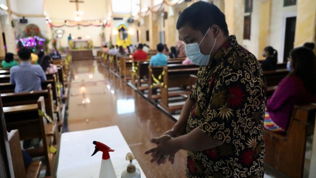 Seorang jemaat mencuci tangan dengan hand sanitizer sebelum melaksanakan ibadat Misa Malam Natal di Gereja Katolik Hati Kudus, Banda Aceh, Kamis (24/12). Foto: Suparta/acehkini 