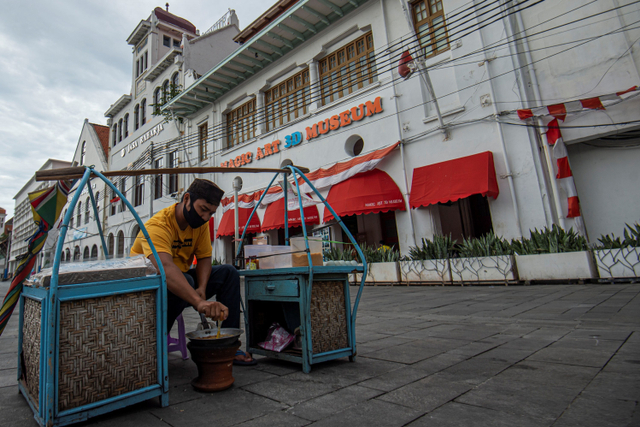 Pedagang jajanan kerak telor menunggu pembeli di kawasan Kota Tua, Jakarta, Kamis (24/12). Foto: Aditya Pradana Putra/ANTARA FOTO