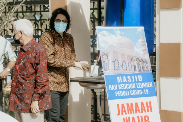 Warga terlihat mengenakan masker dan mencuci tangan saat datang ke prosesi pernikahan di Masjid Haji Keuchik Leumiek, Banda Aceh, guna mencegah penularan virus corona, Sabtu (12/12). Foto: Abdul Hadi/acehkini
