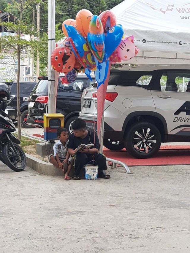 Wahyu bersama adiknya Putra di depan pusat perbelanjaan sedang membaca Al-Qur'an (Iqra). Foto: Dok Muhammad Raflee.