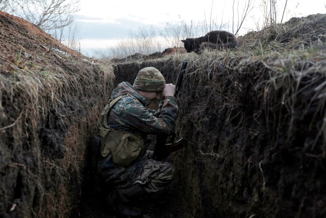 Seekor kucing menatap seorang tentara Ukraina yang sedang beristirahat di paris garis depan dengan separatis yang di dukung Rusia di desa Krasnogorivka, wilayah Donetsk, Ukraina, pada 10 Maret 2020. Foto: Anatolii STEPANOV / AFP