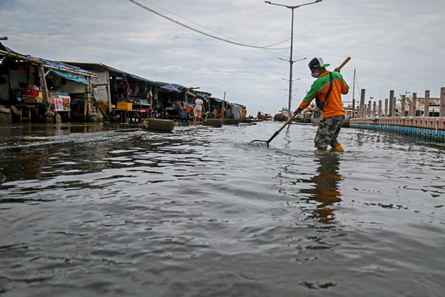Petugas kebersihan membersihkan sampah saat banjir rob di Pelabuhan Kali Adem, Muara Angke, Jakarta, Jumat (1/1).  Foto: Galih Pradipta/ANTARA FOTO