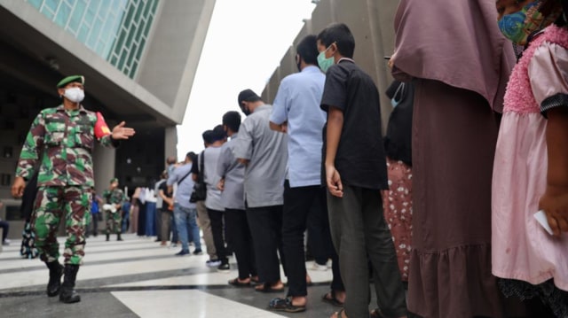 Personel TNI mengatur antrean pengunjung di pintu masuk Museum Tsunami Aceh untuk jaga jarak, Sabtu (2/1), seiring dibuka kembali sejak 31 Desember 2020. Foto: Suparta/acehkini