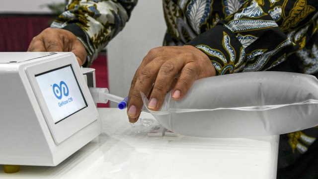 Ketua Konsorsium Riset dan Inovasi COVID-19 Kemenristek Ali Ghufron Mukti menyambungkan kantong berisi hembusan nafasnya dengan alat GeNose C19 di Kantor Kemenko PMK, Jakarta, Kamis (7/1/2021). Foto: M RISYAL HIDAYAT/ANTARA FOTO