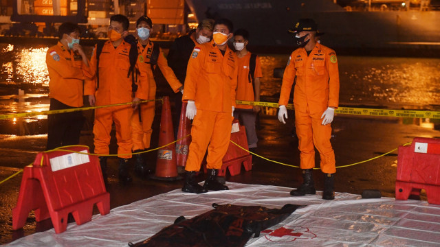 Petugas Basarnas membawa kantong berisi diduga serpihan dari pesawat Sriwijaya Air SJ 182 rute Jakarta - Pontianak yang hilang kontak di perairan Pulau Seribu, di Dermaga JICT, Jakarta, Sabtu (9/1/2021). Foto: Akbar Nugroho Gumay/ANTARA FOTO