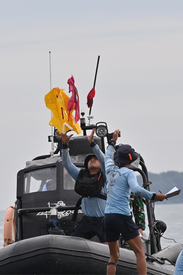 Petugas mengevakuasi pelampung dan kaus anak berwarna pink yang diduga milik penumpang Sriwijaya Air penerbangan SJ182 yang jatuh ke laut. Foto: Adek Berry/AFP