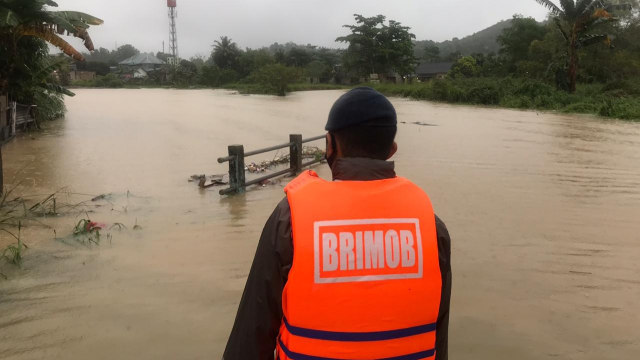Personel Brimob Polda Kepri melihat genangan air disalah satu wilayah Batam, Kepulauan Riau. Foto: Dok Polda Kepri.