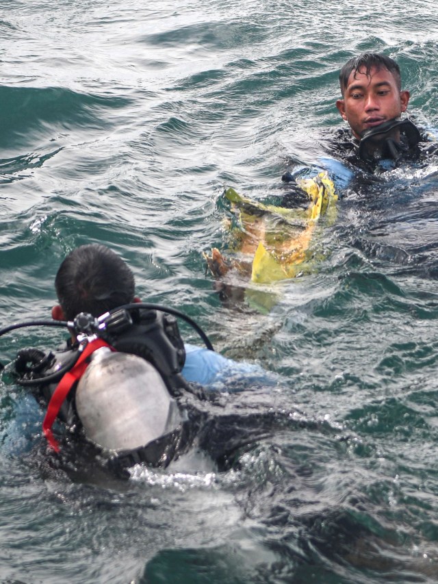 Prajurit Satuan Komando Pasukan Katak (Satkopaska) Armada 1 berusaha mengangkat puing pesawat Sriwijaya Air SJ 182. Foto: M Risyal Hidayat/Antara Foto