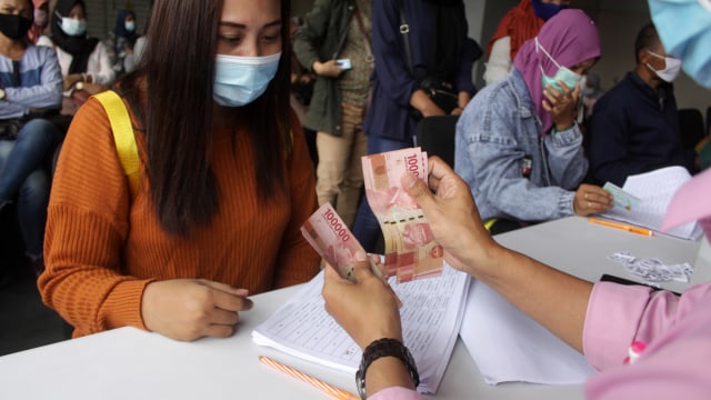 Warga menerima uang Bantuan Langsung Tunai (BLT) karyawan korban pemutusan hubungan kerja (PHK). Foto: ANTARA FOTO/Umarul Faruq