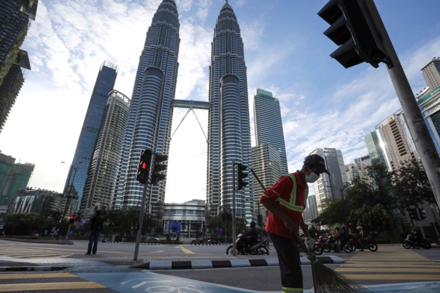 Seorang petugas kebersihan jalan bekerja di depan Menara Kembar Petronas, saat lockdown di Kuala Lumpur, Malaysia. Foto: Lim Huey Teng/Reuters
