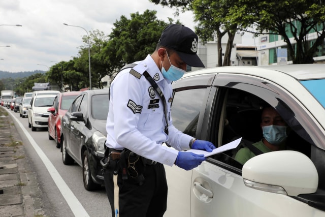 Polisi memeriksa dokumen pengendara saat lockdown di Kuala Lumpur, Malaysia. Foto: Lim Huey Teng/Reuters