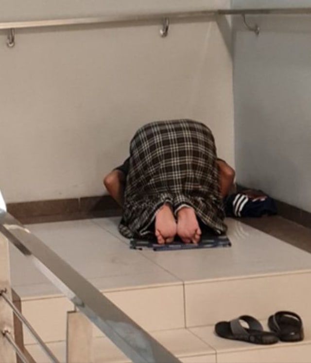 Potret seorang kakek salat di tangga rumah sakit. (Foto: @asaibraim/Twitter)