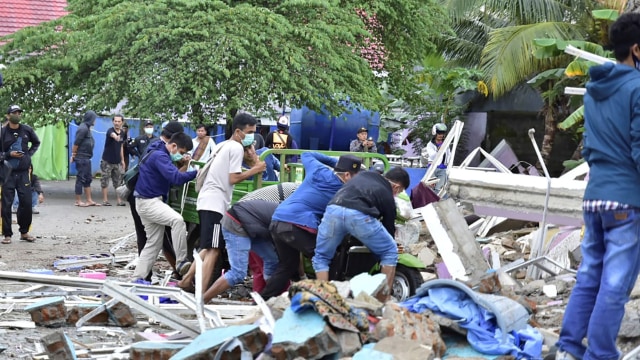 Tim penyelamat mencari korban di sebuah bangunan yang runtuh akibat diguncang gempa di kota Mamuju, Sulawesi Barat, Jumat (15/1). Foto: FIRDAUS/AFP
