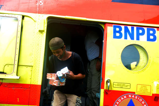 Warga korban gempa bumi memindahkan bantuan logistik dari helikopter Badan Nasional Penanggulangan Bencana (BNPB) yang mendarat di Kecamatan Malunda, Kabupaten Majene, Sulawesi Barat, Rabu (20/1).  Foto: Abriawan Abhe/ANTARA FOTO