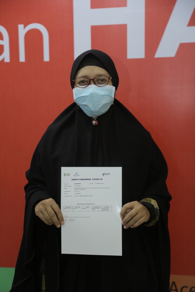 Seorang Nakes di RSUDZA Banda Aceh menunjukkan kartu vaksinasi corona. Foto: Abdul Hadi/acehkini
