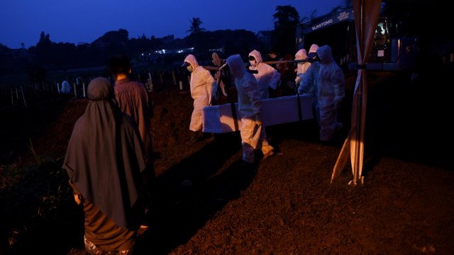 Petugas yang mengenakan APD bersiap membawa peti berisi jenazah dengan protokol COVID-19 di TPU Srengseng Sawah, Jakarta, Kamis (21/1). Foto: Wahyu Putro A/ANTARA FOTO