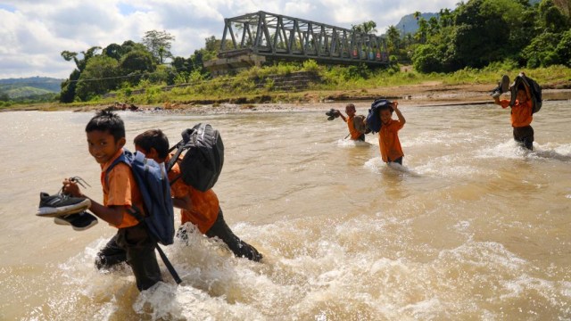 Siswa di Gampong Panca Kubu, Lembah Seulawah, Kabupaten Aceh Besar, Aceh, menyeberangi sungai saat pulang sekolah pada Jumat (22/1). Foto: Suparta/acehkini