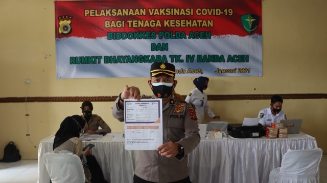 Polisi yang bertugas di RS Bhayangkara Polda Aceh menunjukkan kartu vaksinasi corona. Foto: Polda Aceh