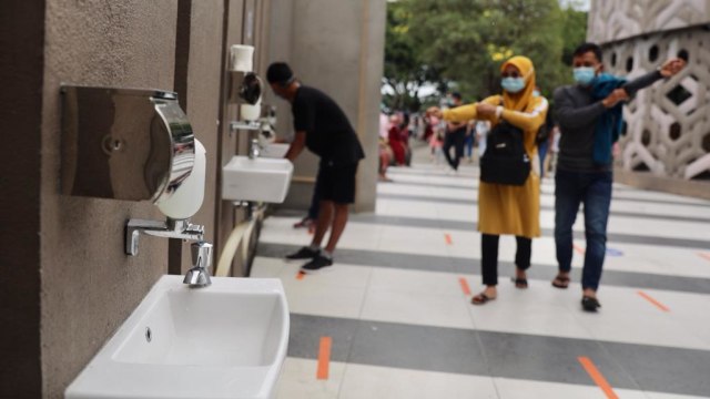 Pengunjung Museum Tsunami Aceh terlihat mengenakan masker dan mencuri tangan sebelum masuk ke dalam museum pada Sabtu (2/1), seiring dibuka kembali sejak 31 Desember 2020. Foto: Suparta/acehkini
