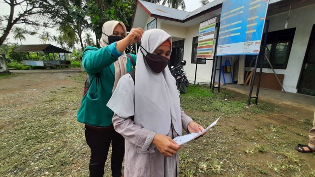 Mahasiswa KKN Universitas Syiah Kuala (USK) memakai masker kepada warga saat membagikan masker gratis di Desa Lambitra, Aceh Besar. Foto: Dok. acehkini