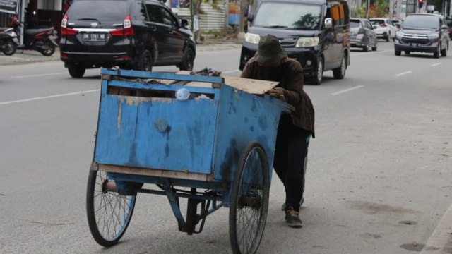 Kakek Hartono, pemulung di Palu tengah mendorong gerobaknya menyusuri jalan-jalan di pusat Kota Palu, Sabtu (30/1). Foto: Rian/PaluPoso