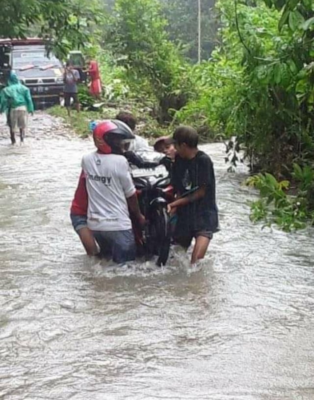 Warga menggendong motor saat menyebrang sungai. Foto: istimewa.