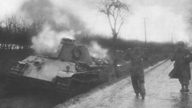 Seorang tentara Amerika mengawal seorang awak Jerman dari tanknya yang hancur pada Pertempuran Bulge. | Wikimedia Commons