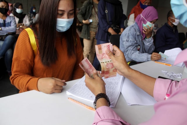 Warga menerima uang Bantuan Langsung Tunai (BLT) karyawan korban pemutusan hubungan kerja (PHK) di Bank Delta Arta, Sidoarjo, Jawa Timur, Senin (14/12). Foto: Umarul Faruq/Antara Foto