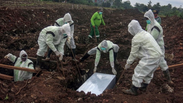 Ilustrasi petugas pemakaman menguburkan jenazah korban COVID-19. Foto: Yulius Satria Wijaya/ANTARA FOTO
